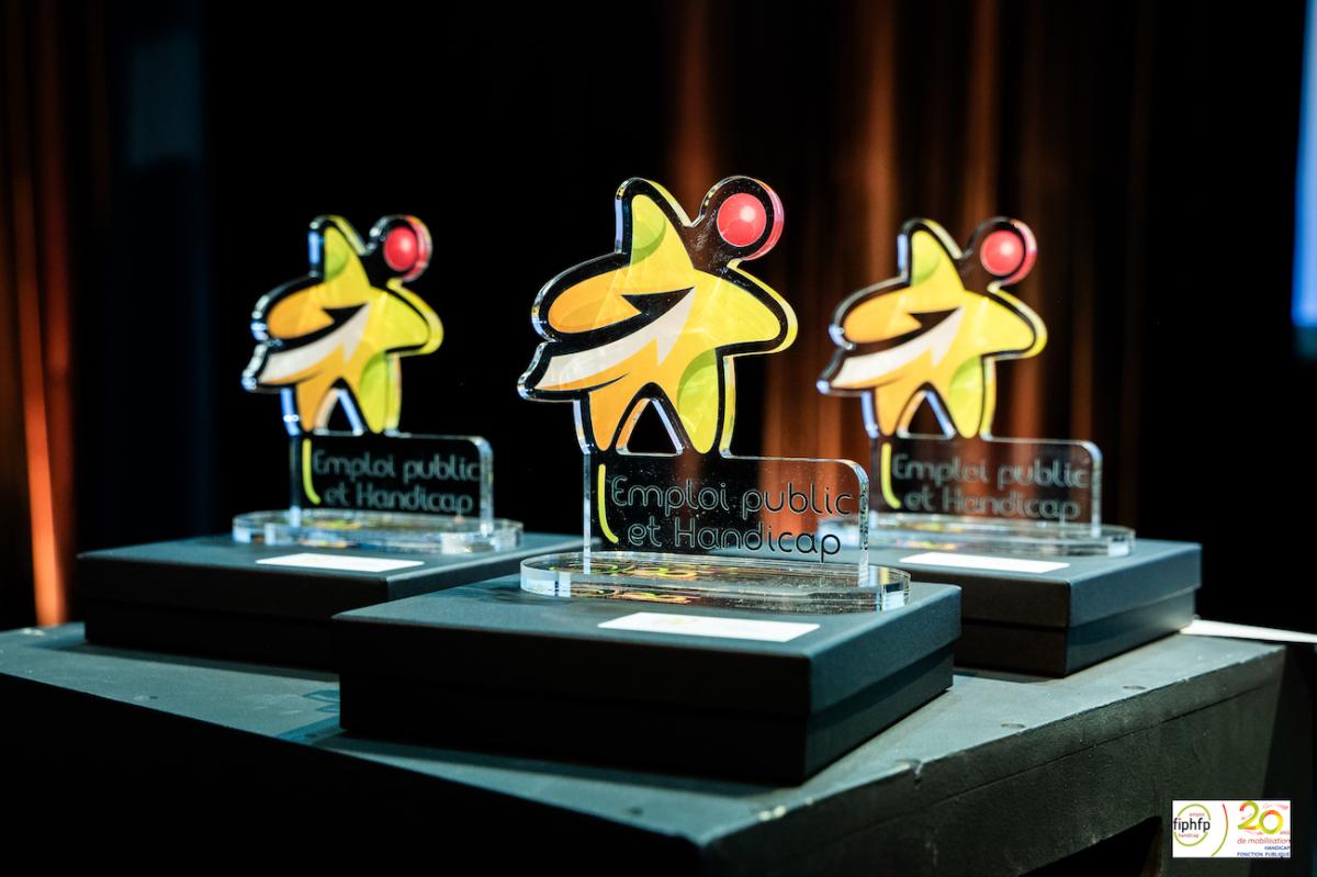 Photo représentant 3 trophées en forte d'étoile où il est écrit Emploi public et handicap avec le logo du FIPHFP